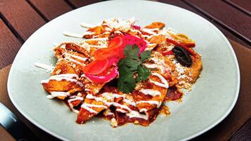 A plate of nachos with toppings and a knife on the side.