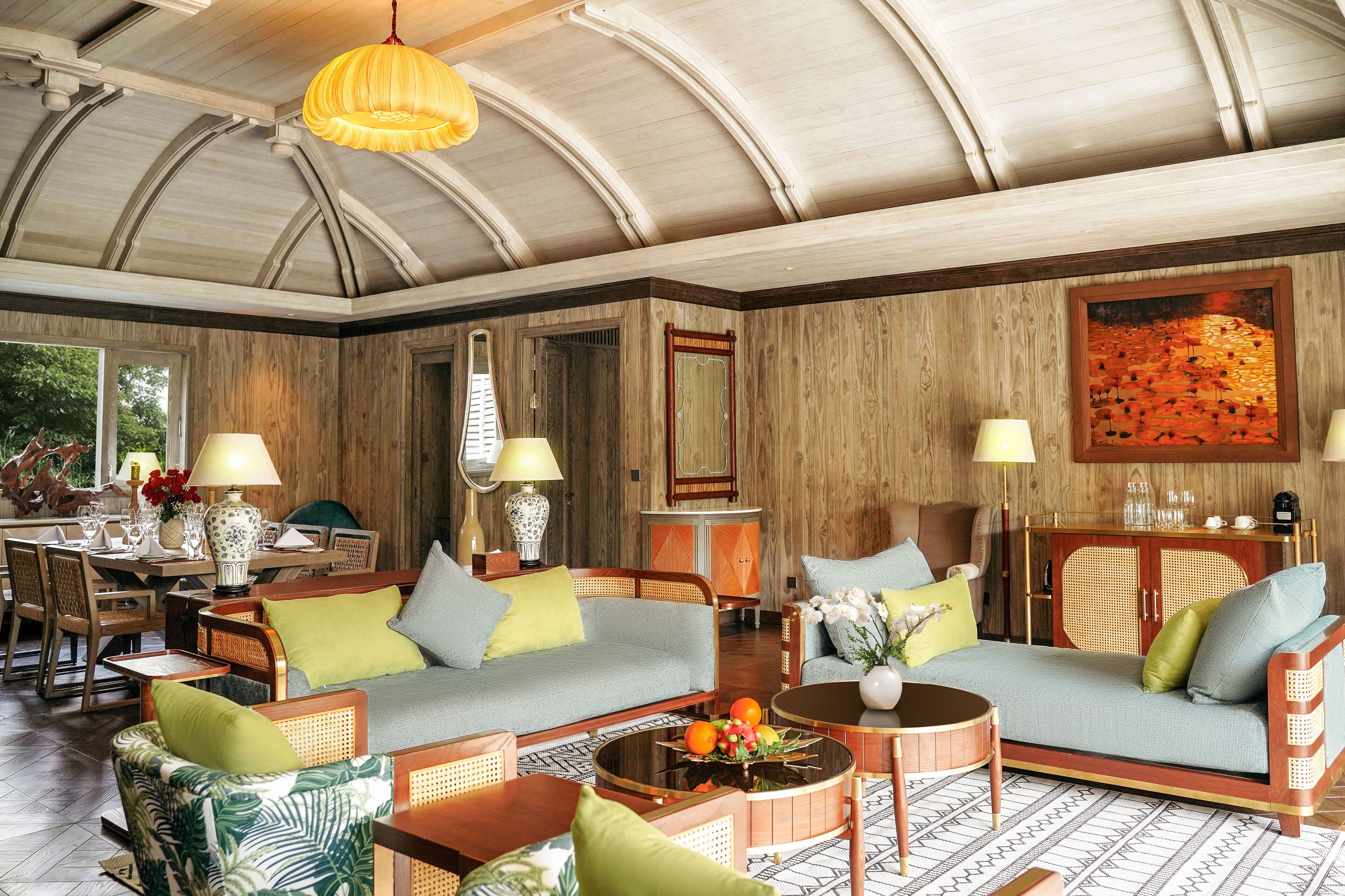 Een ruime woonkamer met een hoog gewelfd plafond, houten paneelwanden en een eethoek met een houten tafel en stoelen.
