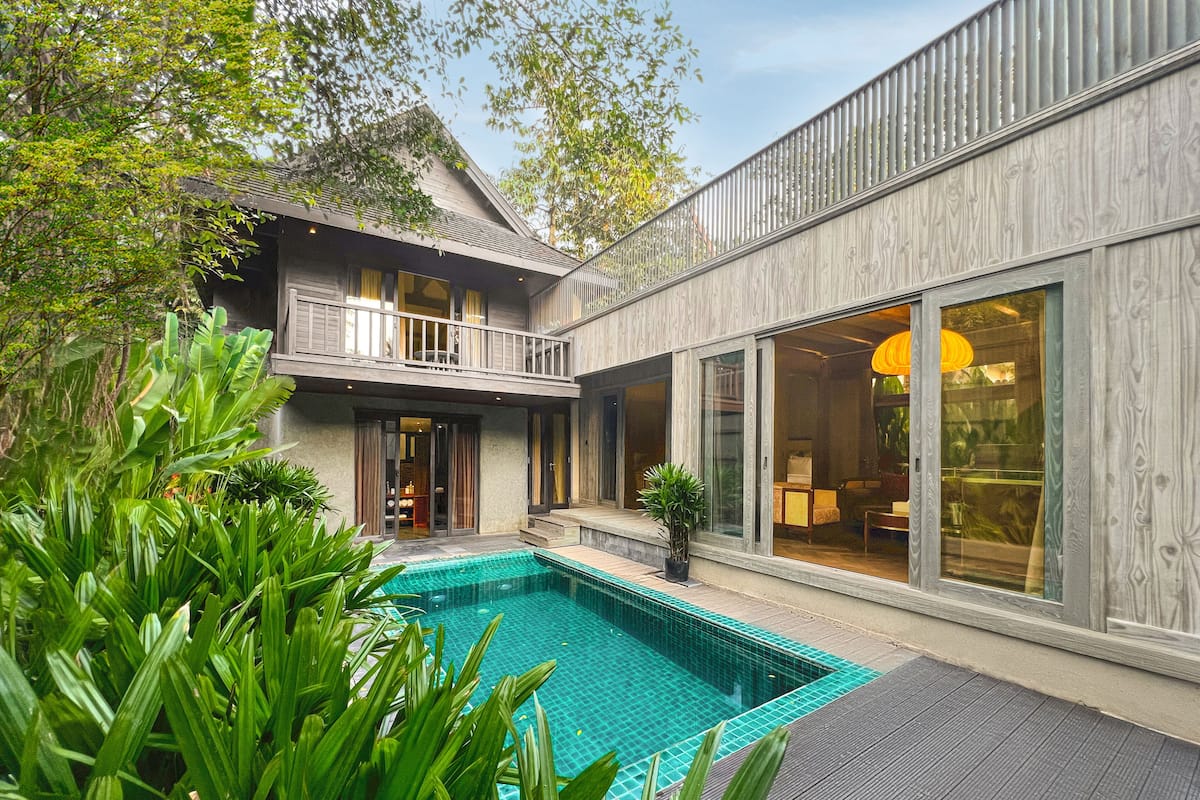 A modern house with a swimming pool, large windows, and a balcony.