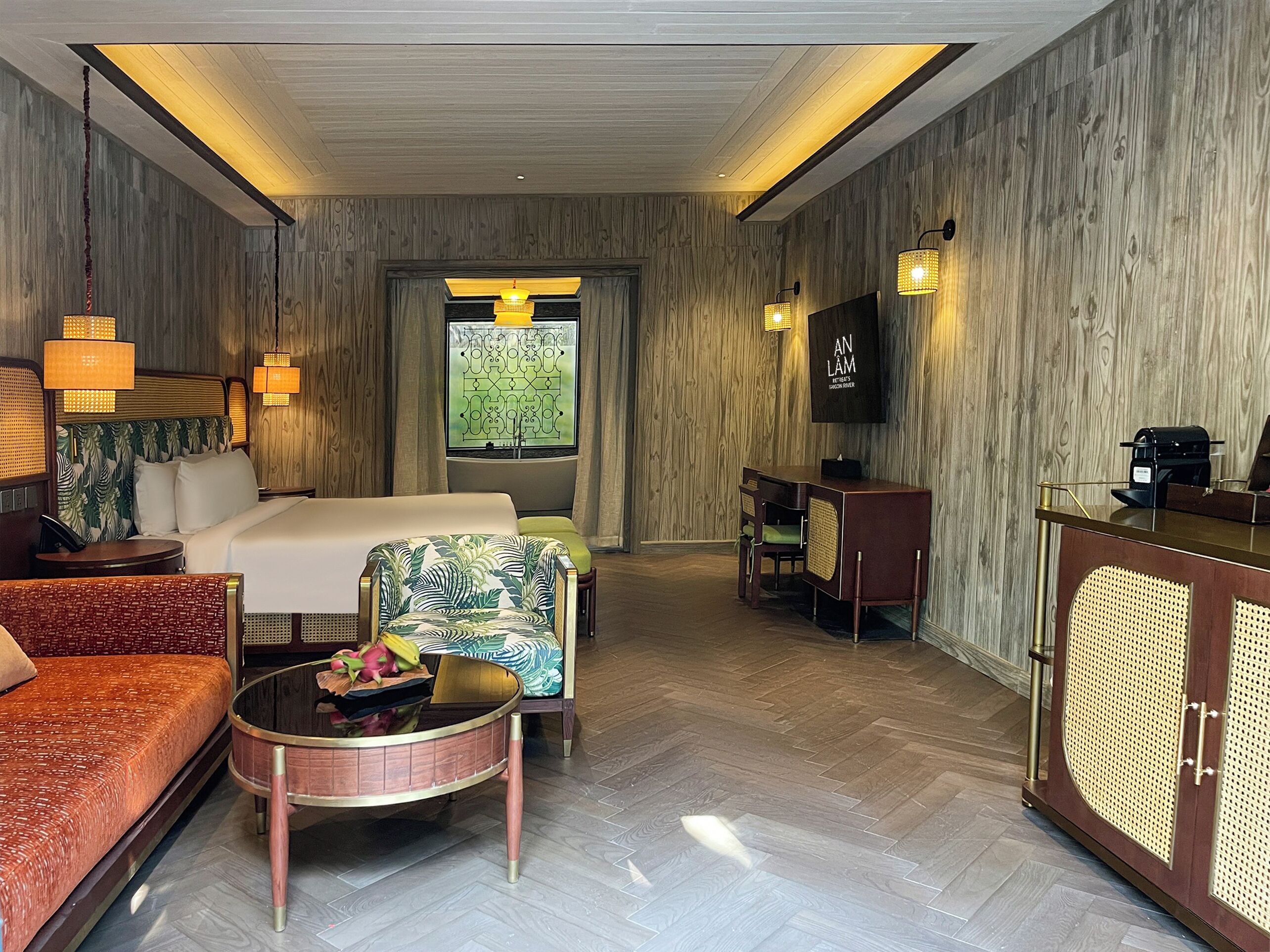 Una habitación de hotel con cama, sofá, mesa de centro, escritorio y televisor.