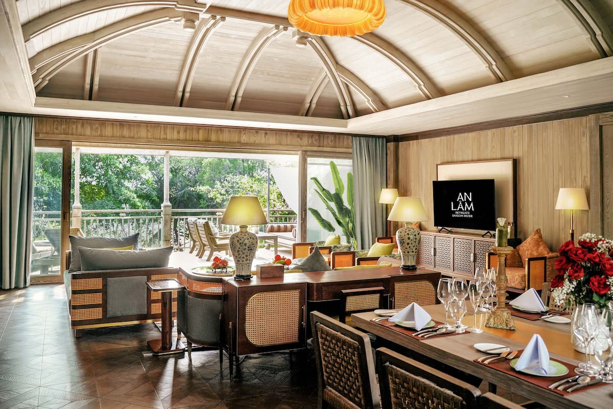 A well-appointed dining area with a high ceiling, large windows, and a view of greenery outside.
