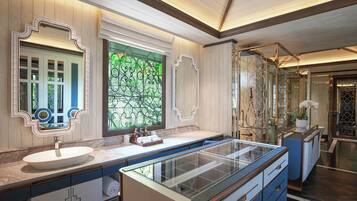 A modern bathroom with a large glass-enclosed shower, a white sink, and a decorative mirror.