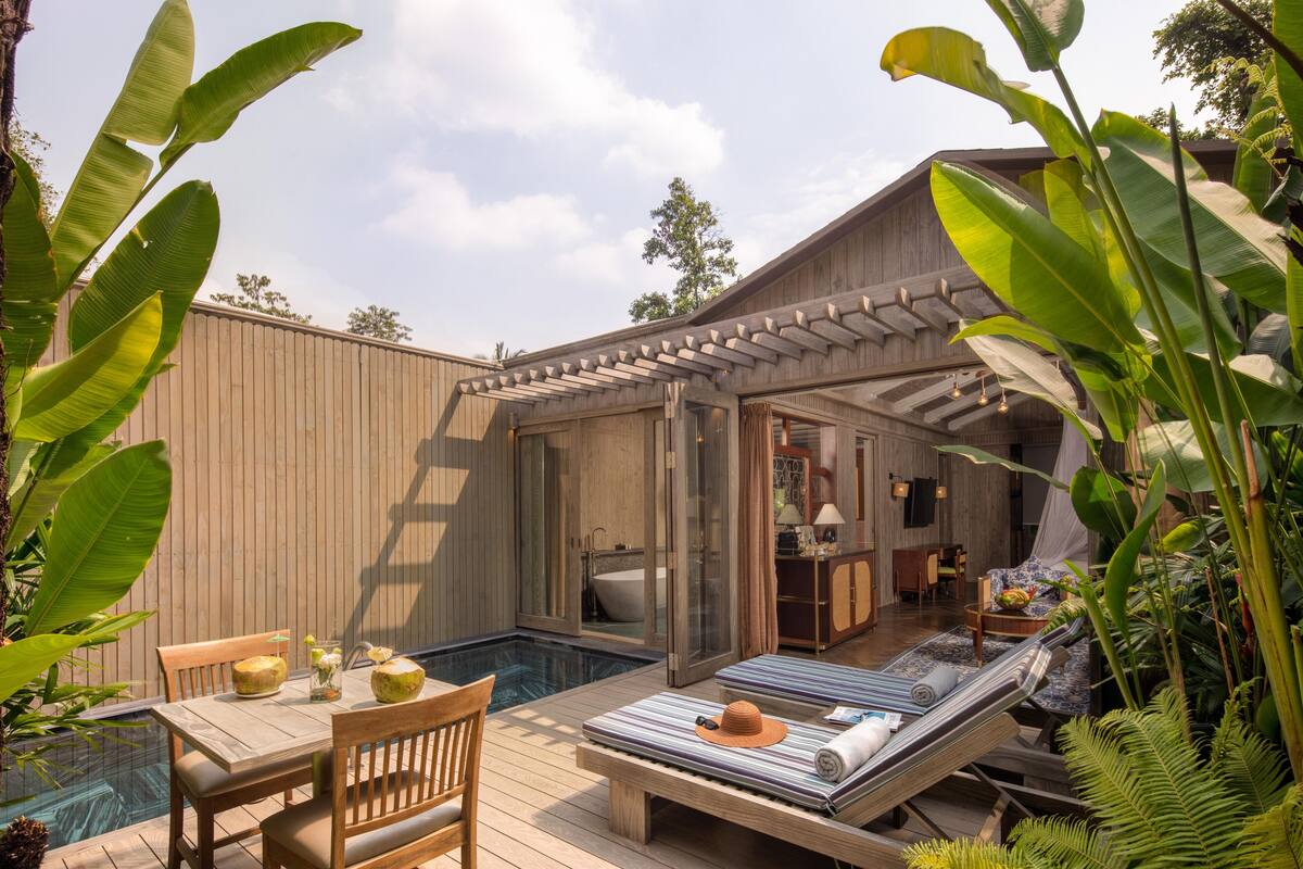 A wooden deck with a pool, a lounge area with a hammock, and a bathroom with a bathtub.