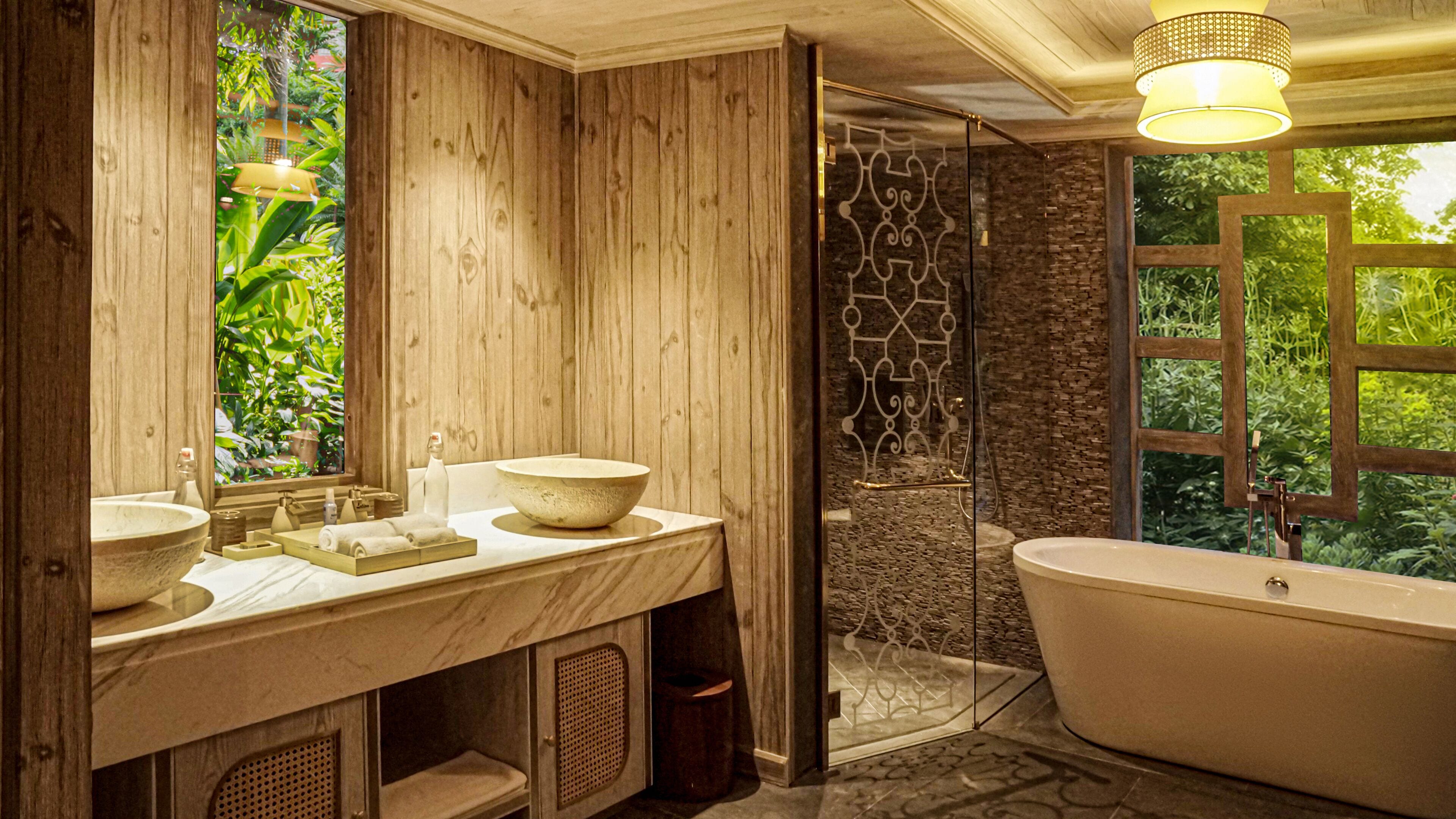 A bathroom with wooden paneling, a freestanding bathtub, and a large window with a view of greenery.