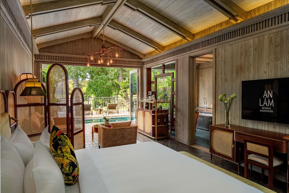 A spacious bedroom with a large bed, a TV, and a view of an outdoor pool area.
