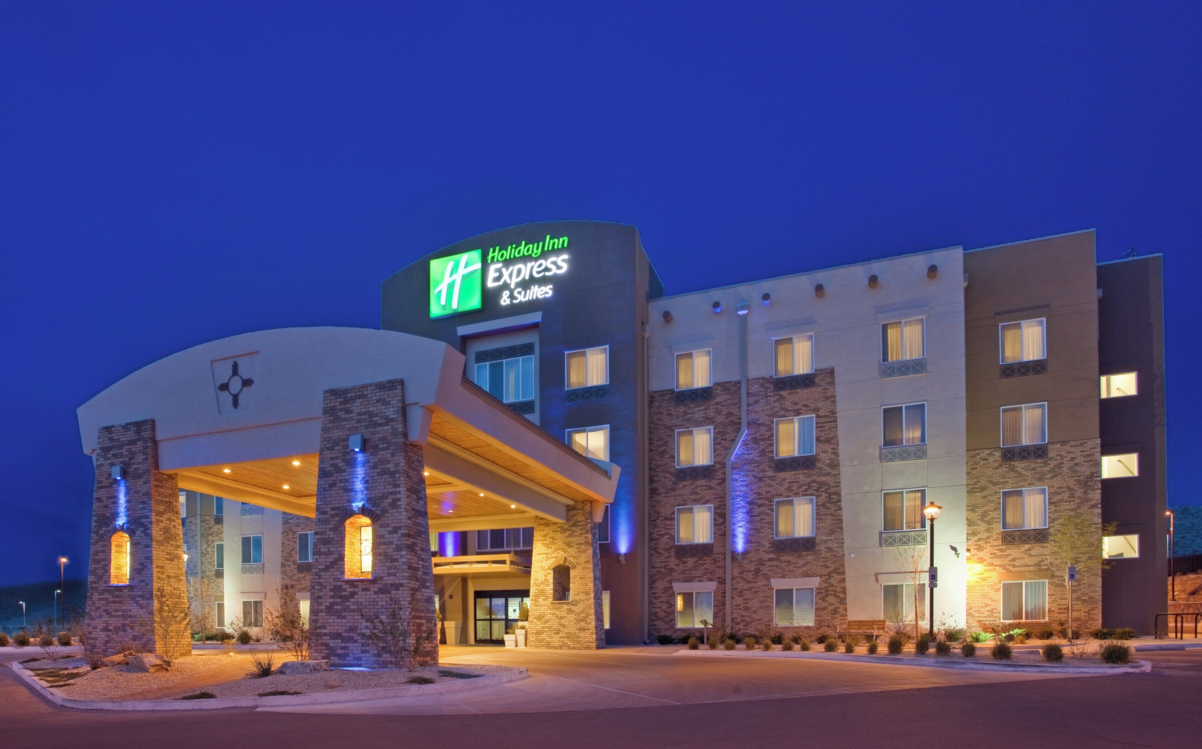 A Holiday Inn Express & Suites hotel with a brick facade, multiple windows, and a well-lit entrance.