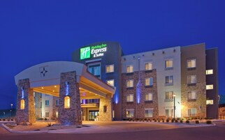Un hotel Holiday Inn Express & Suites con fachada de ladrillo, múltiples ventanas y una entrada bien iluminada.