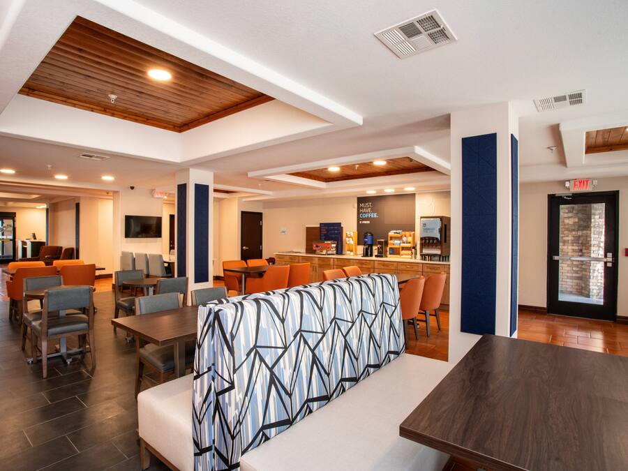 A modern hotel lobby with seating areas, a bar, and a reception desk.