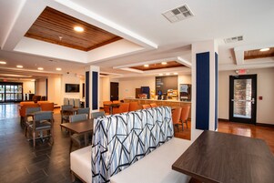 Un moderno vestíbulo de hotel con zonas de estar, un bar y una recepción.