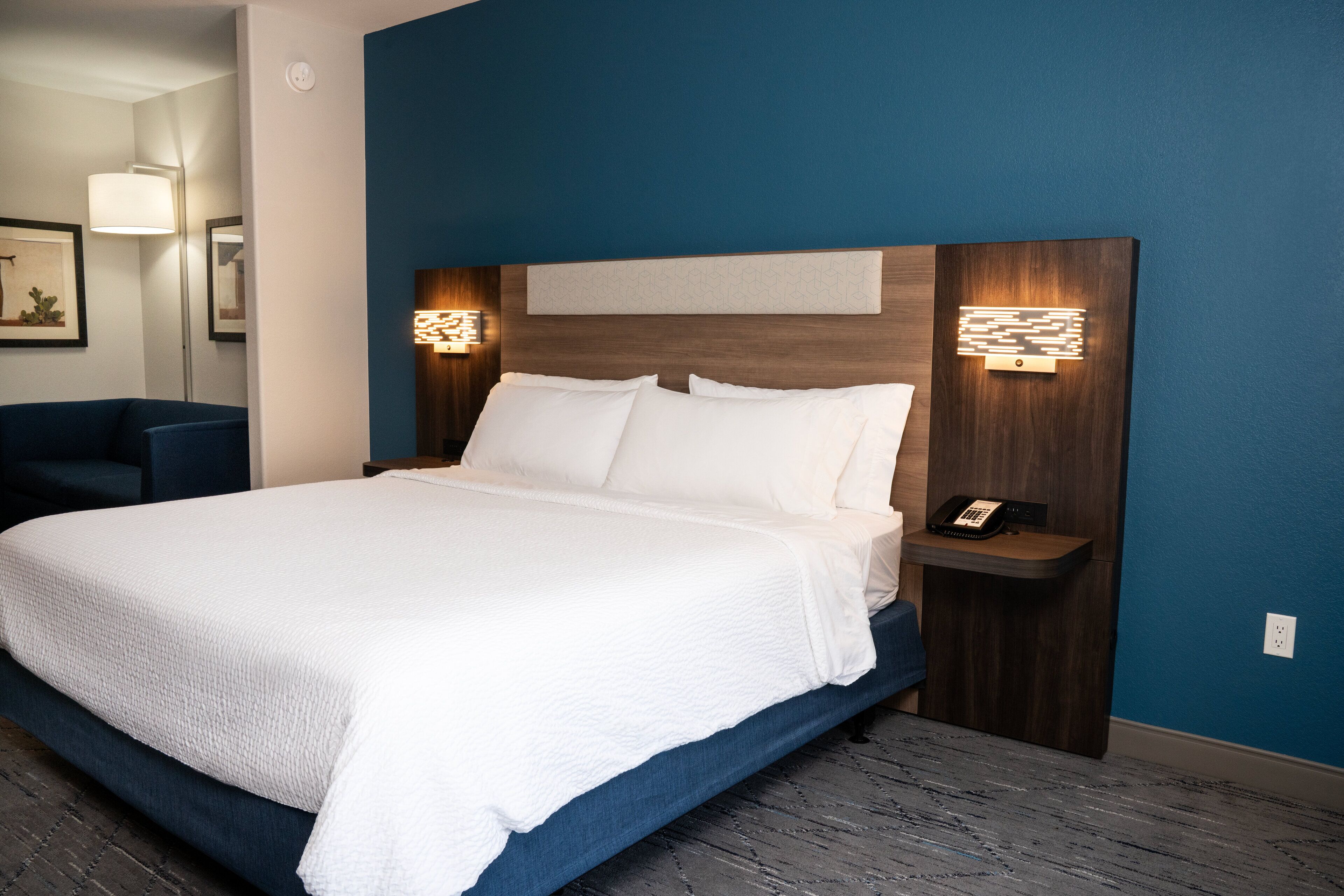 A neatly made bed with white linens, a wooden headboard, and bedside lamps.