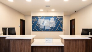 A reception area with two reception desks, a blue geometric wall design, and a sign for 'Holiday Inn Express & Suites'. - Holiday Inn Express & Suites Las Cruces North by IHG (Las Cruces)
