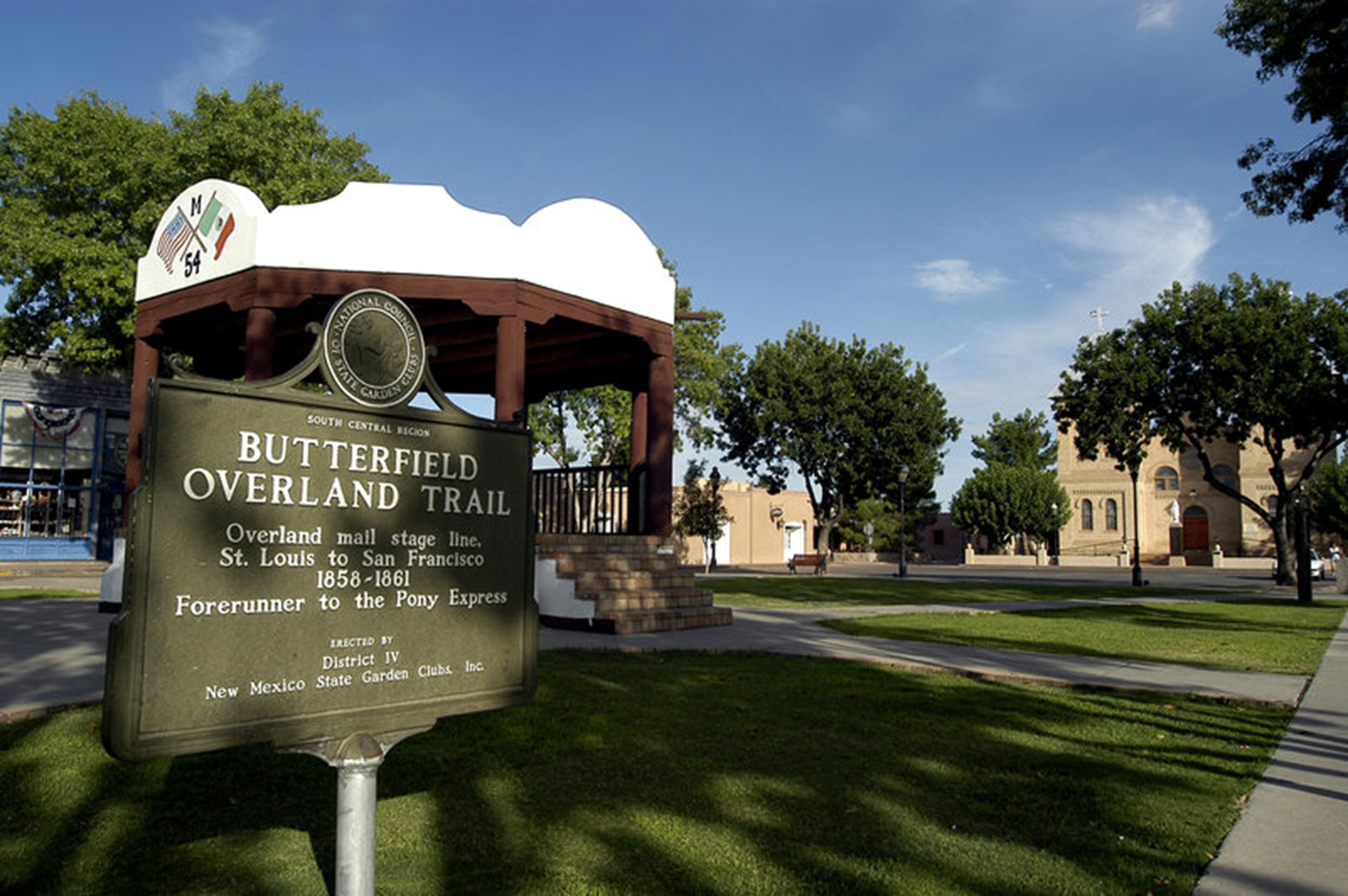 Placa histórica da Trilha Overland Butterfield, com uma estrutura de madeira e céu claro ao fundo.