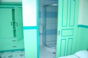 Enjoy a refreshing shower in this stylish bathroom, featuring a shower area with a glass door and a convenient wardrobe with ample storage.