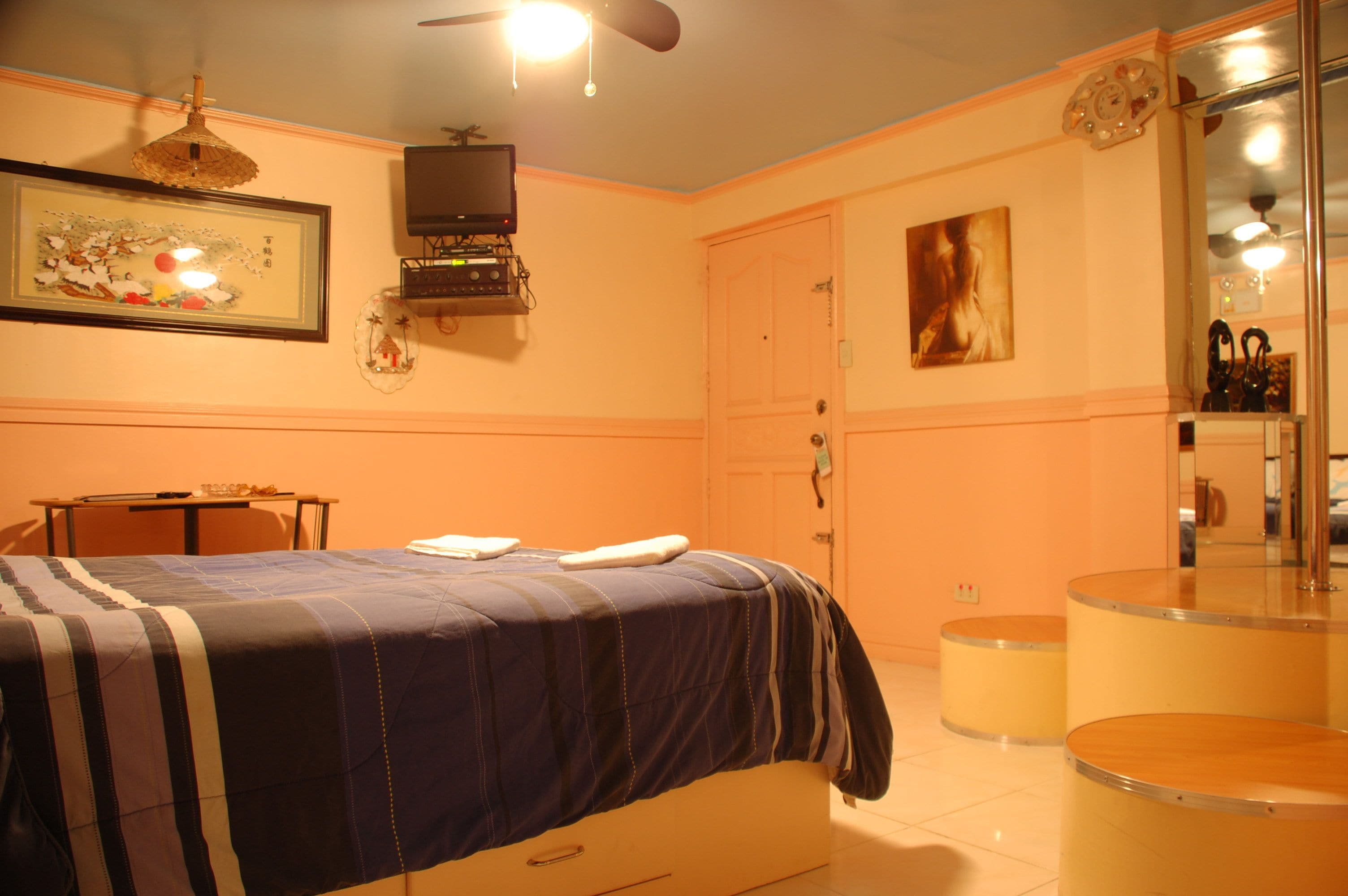 A hotel room with a bed, a desk, a chair, a television, a door, and a mirror.