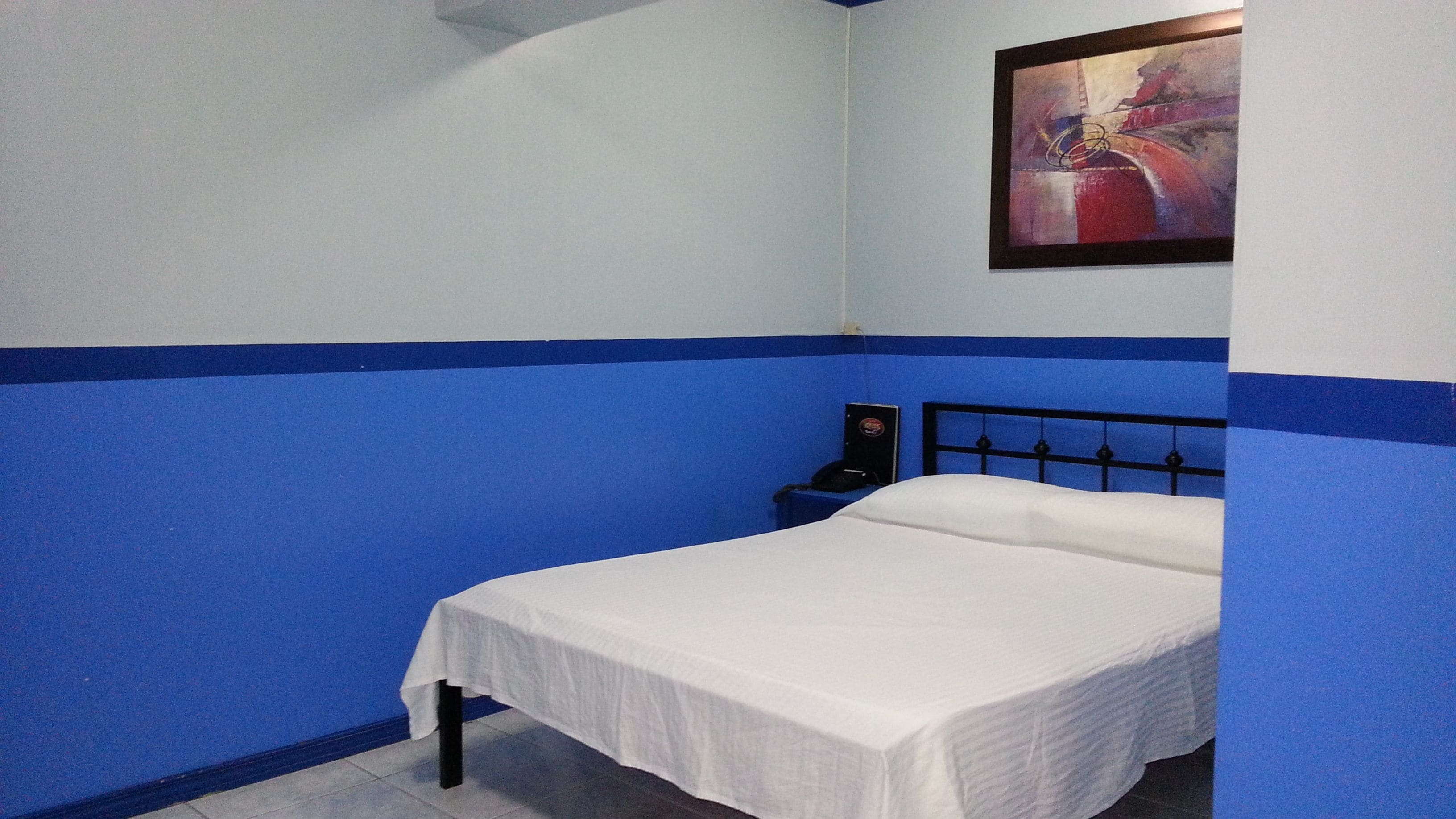 A single bed in a room with blue walls and a white bedspread.