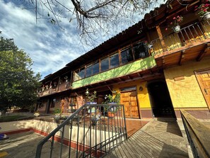 A traditional wooden building with multiple balconies, large windows, and potted plants. - Hotel Huerta Real (Mazamitla)