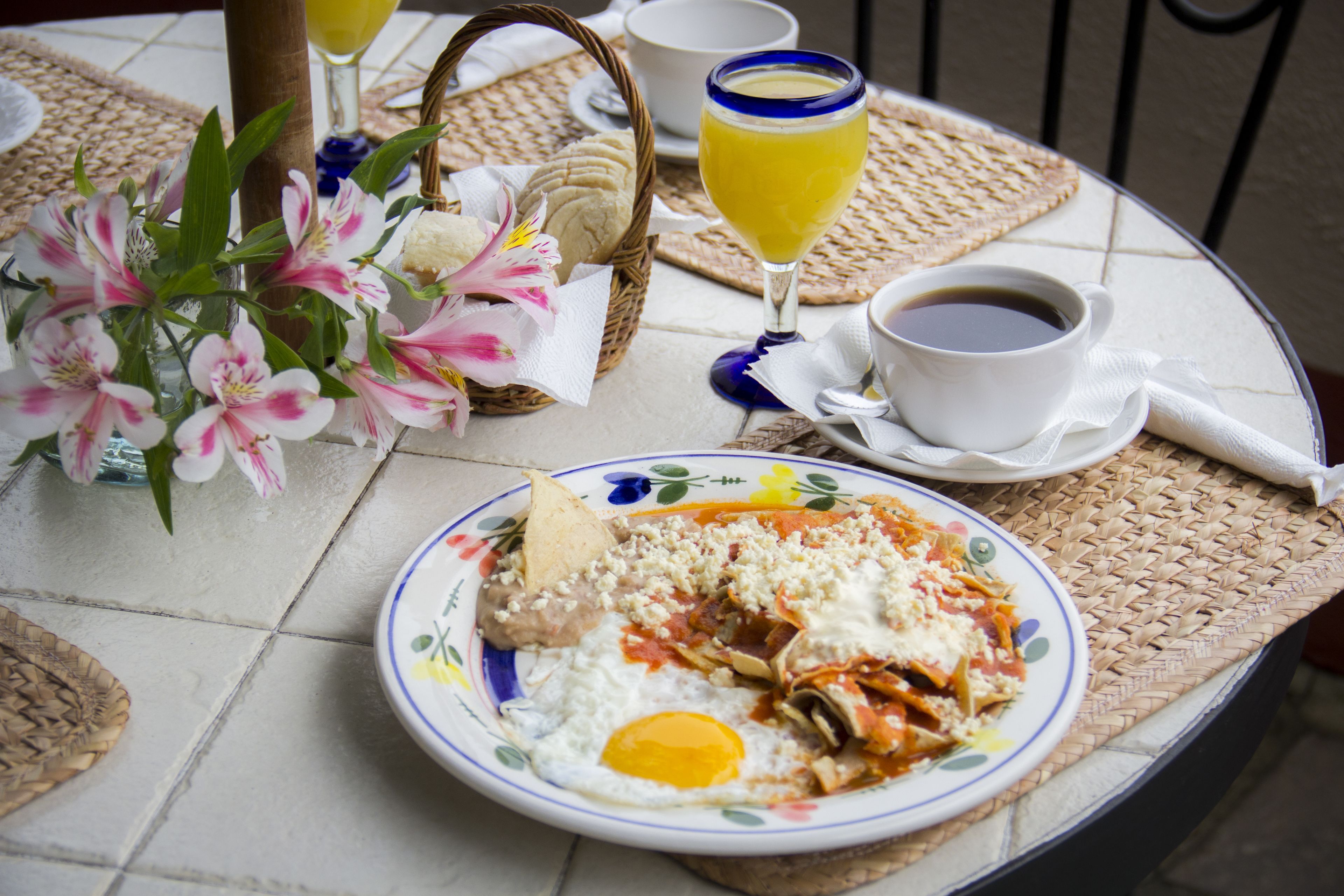 Una colazione servita con un piatto di cibo, una tazza di caffè e un bicchiere di succo d'arancia su un tavolo.