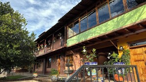 A traditional wooden building with a balcony, potted plants, and a fountain.