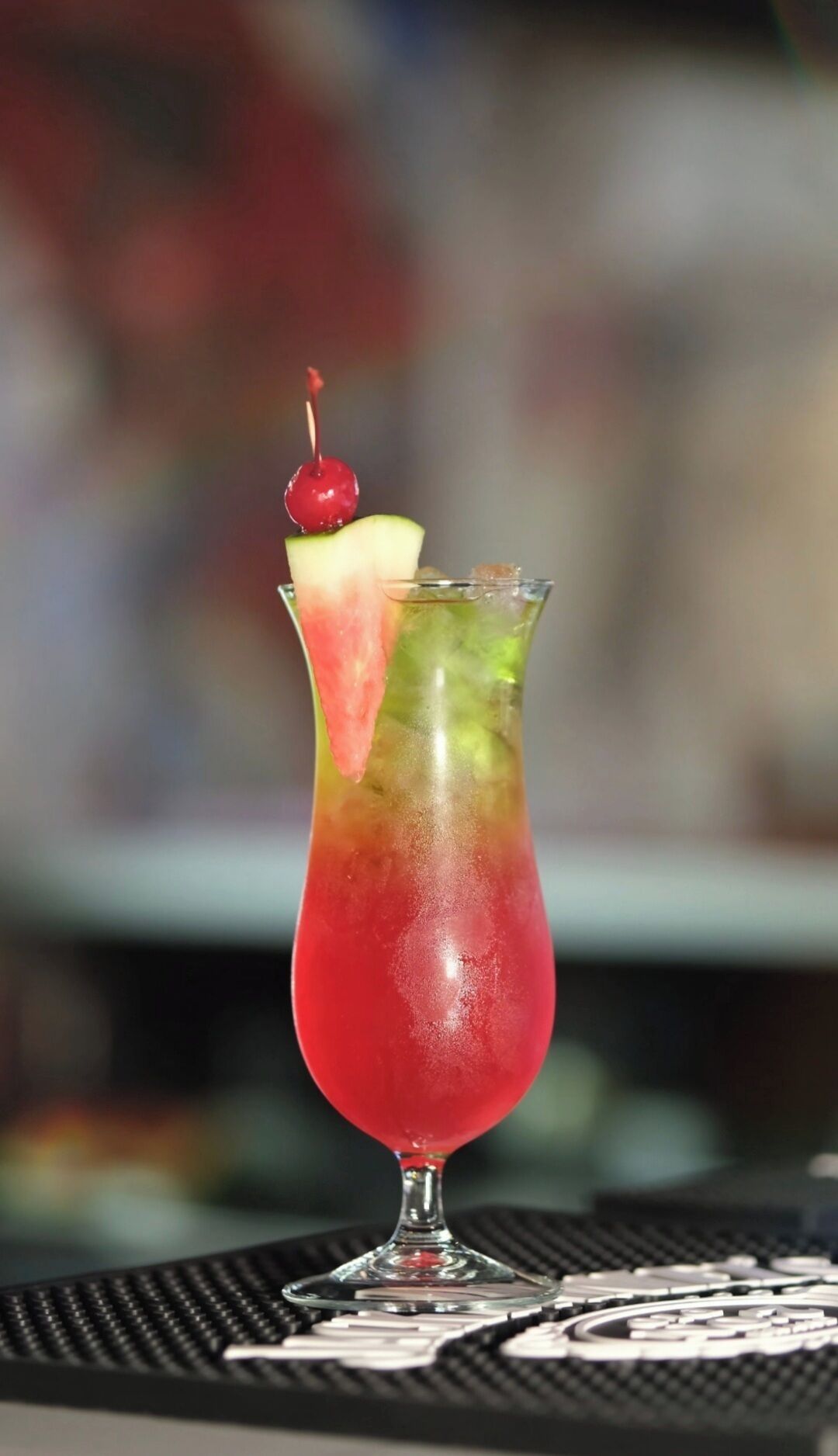 Un cocktail servi dans un grand verre, garni d’une cerise.