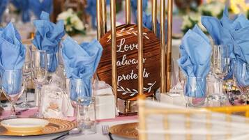 A table set with blue napkins, clear glasses, and a wooden sign with the text "Love always protects".