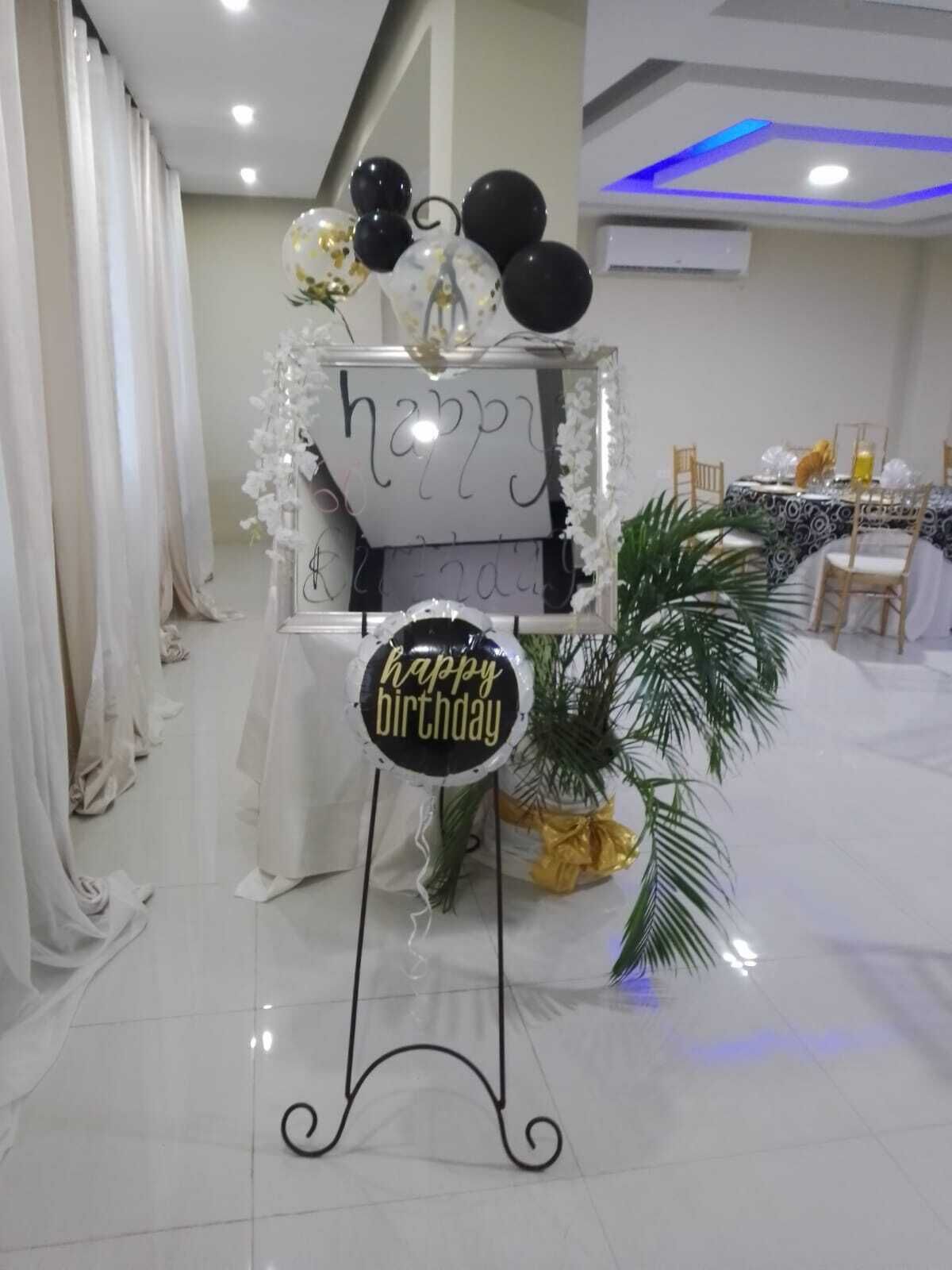 A birthday party setup with a 'happy birthday' sign, balloons, and a table with a patterned tablecloth.