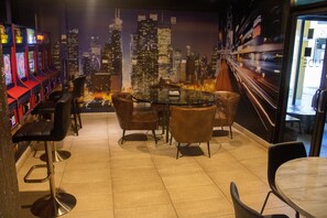 A bar area with a cityscape mural, bar stools, and a round table.