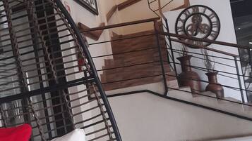 Un escalier avec une rampe en bois et une horloge murale ronde.