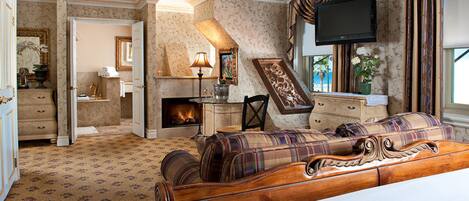 A hotel room with a large bed, a fireplace, a television, and a view of the outdoors.