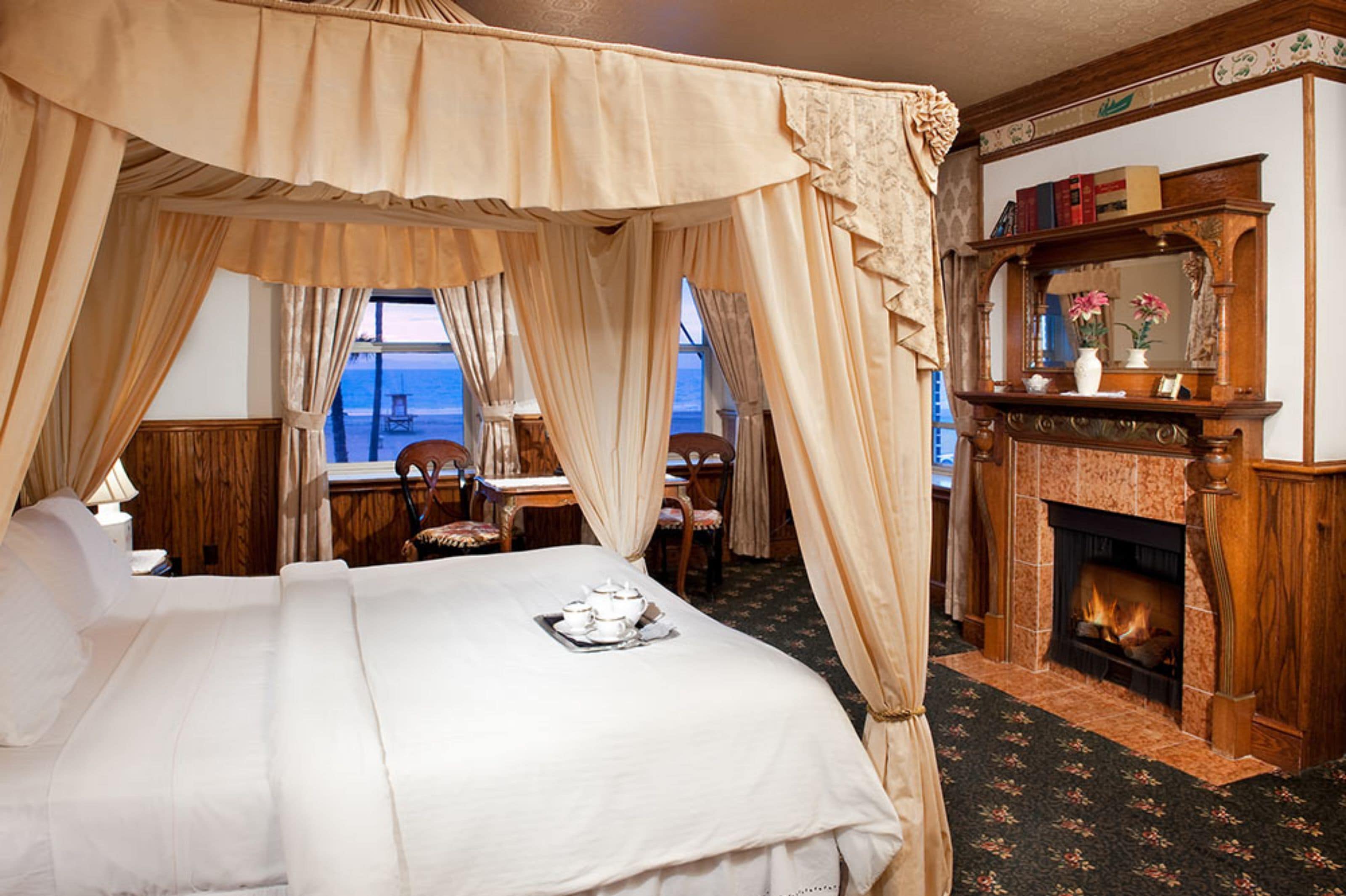 Une chambre à coucher avec un lit à baldaquin, une cheminée et une vue sur la mer.