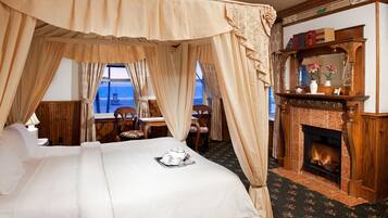 Une chambre à coucher avec un lit à baldaquin, une cheminée et une vue sur la mer.