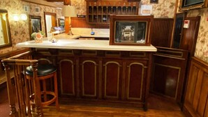 A bar area with a wooden counter, bar stools, a clock, and a chandelier. - Dorymans Oceanfront Inn (Newport Beach)