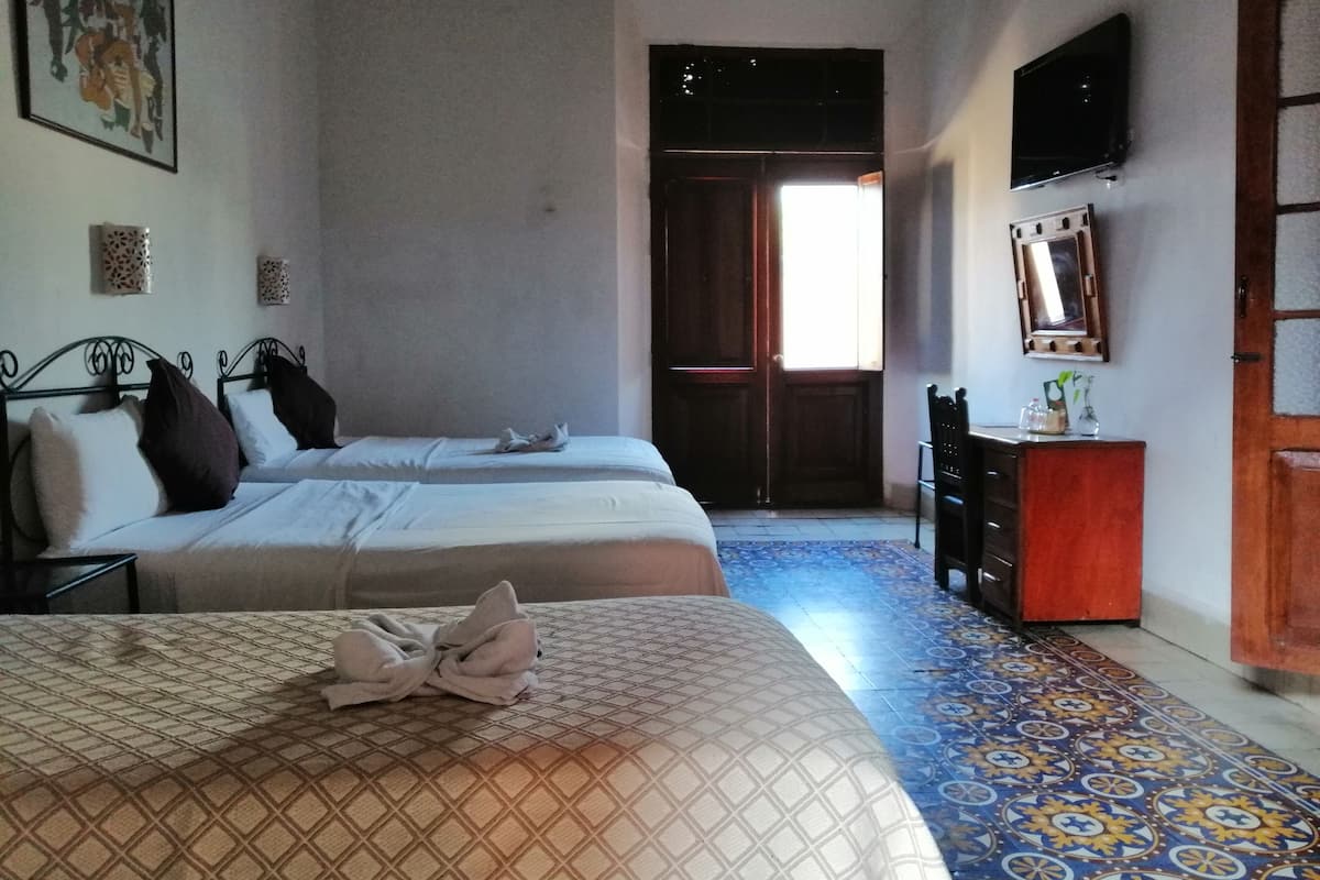 A hotel room with two beds, a television, a dresser, and a patterned floor.