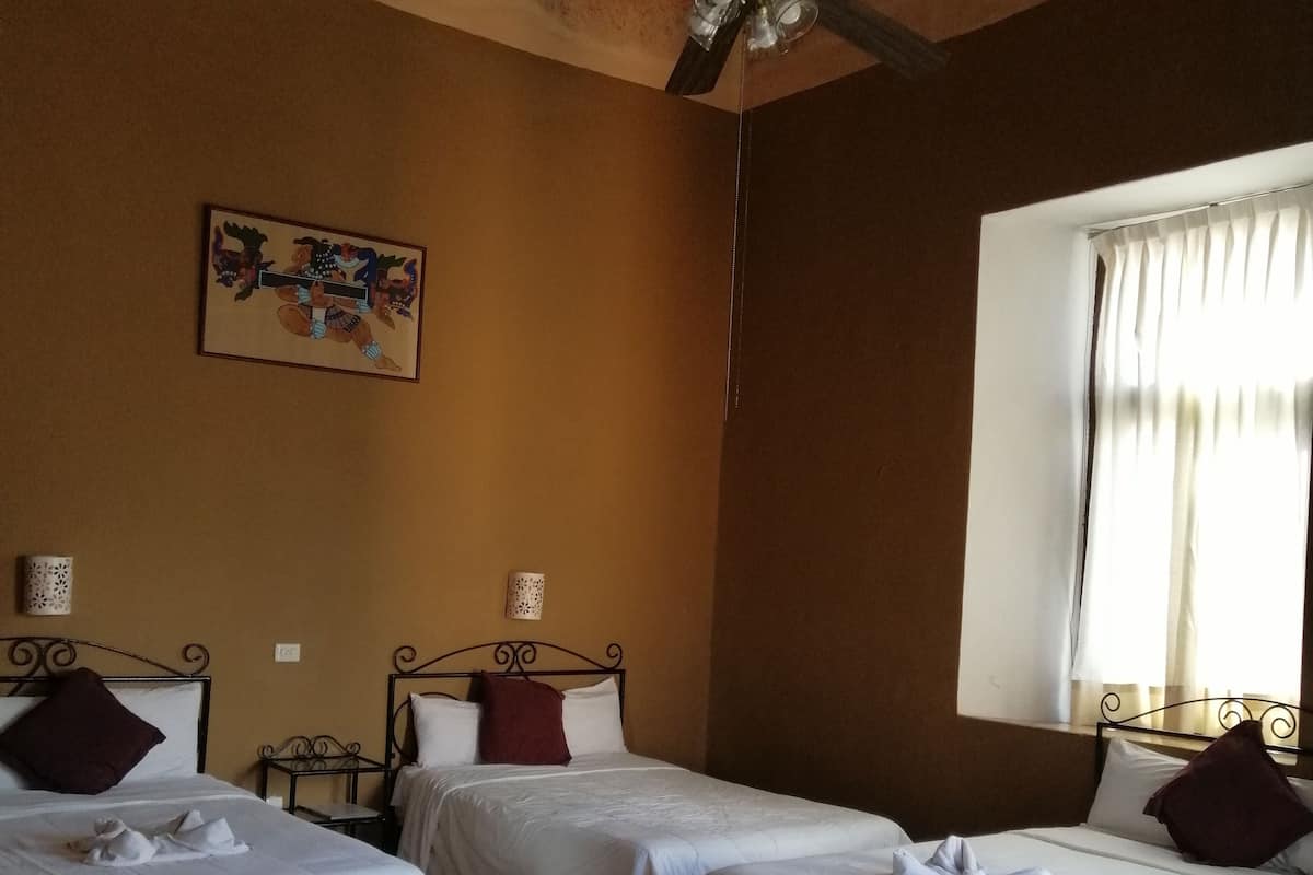 A hotel room with two beds, a ceiling fan, a window with curtains, and a patterned floor.