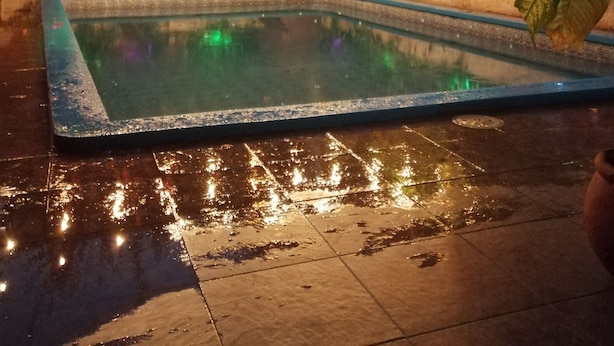 Una piscina con luces cálidas y abundante vegetación.