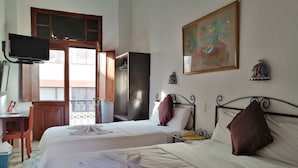 Una habitación de hotel con dos camas, un escritorio, un televisor y una ventana con vistas.