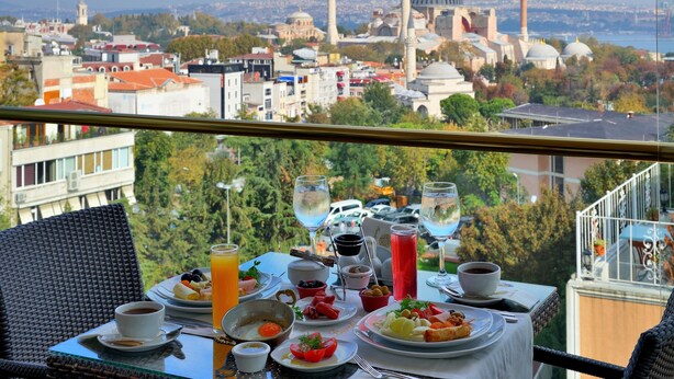 A table set with breakfast items and a view of a cityscape with historical buildings. - Burckin Hotel (Istanbul)