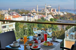 A table set with breakfast items and a view of a cityscape with historical buildings. - Burckin Hotel (Istanbul)