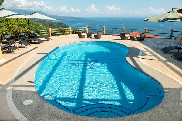 Alberca al aire libre, sombrillas en la alberca y camastros