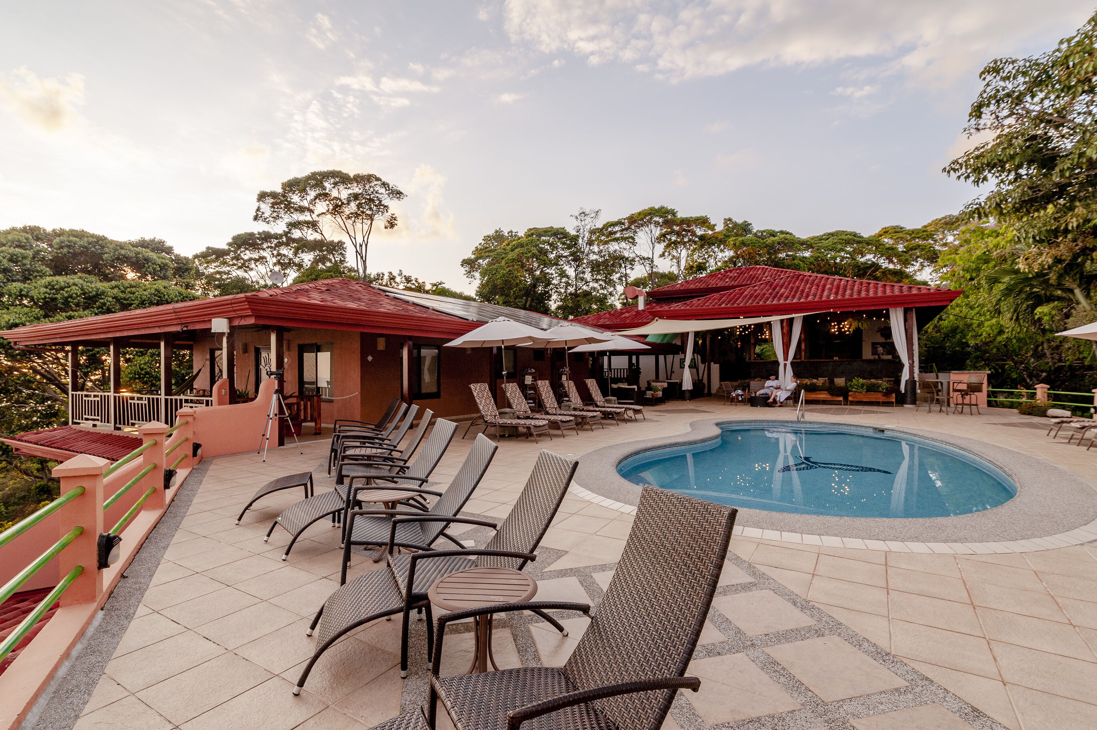 A poolside area with lounge chairs, umbrellas, and a pool.