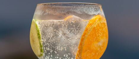 A clear glass with ice cubes, lime, and an orange slice.