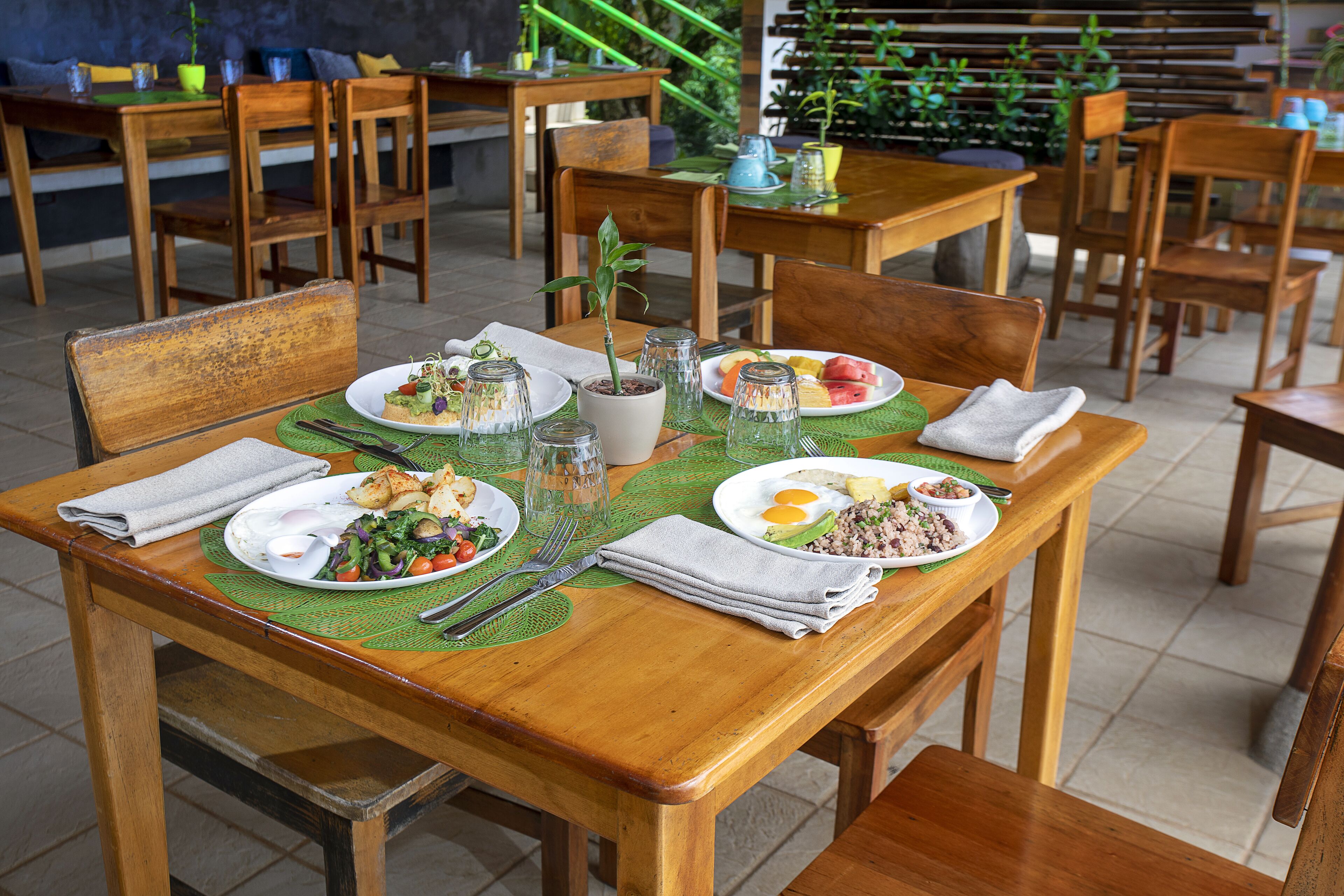 A dining area with wooden tables and chairs, green placemats, and various dishes.