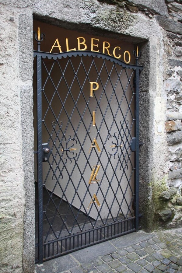 Una reja de hierro forjado con el nombre "ALBERGO" y la palabra "PIAZZA".