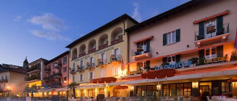 A row of buildings with outdoor seating, some with awnings, and a clear sky.