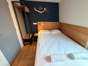 A single bed with white bedding, a wooden headboard, and a nightstand with a lamp. - Hotel Continental Amsterdam (Amsterdam)