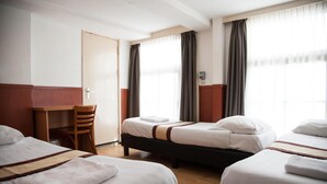 Una habitación de hotel con tres camas, un escritorio y una silla.