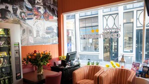 Un vestíbulo de hotel con una recepción, una máquina expendedora y una ventana con vista a la calle.