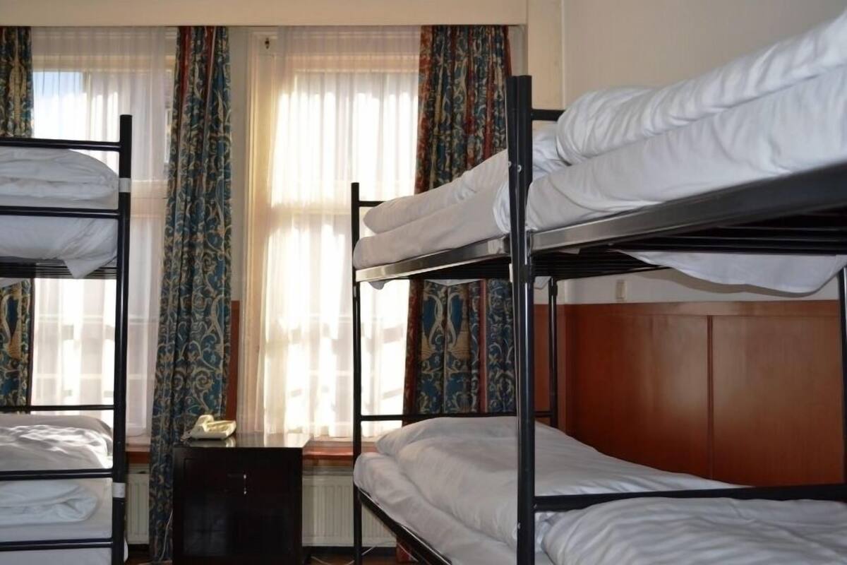 Un dormitorio con literas, una mesita pequeña y cortinas.