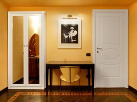A hallway with a table and chair, a framed picture on the wall, and two doors.