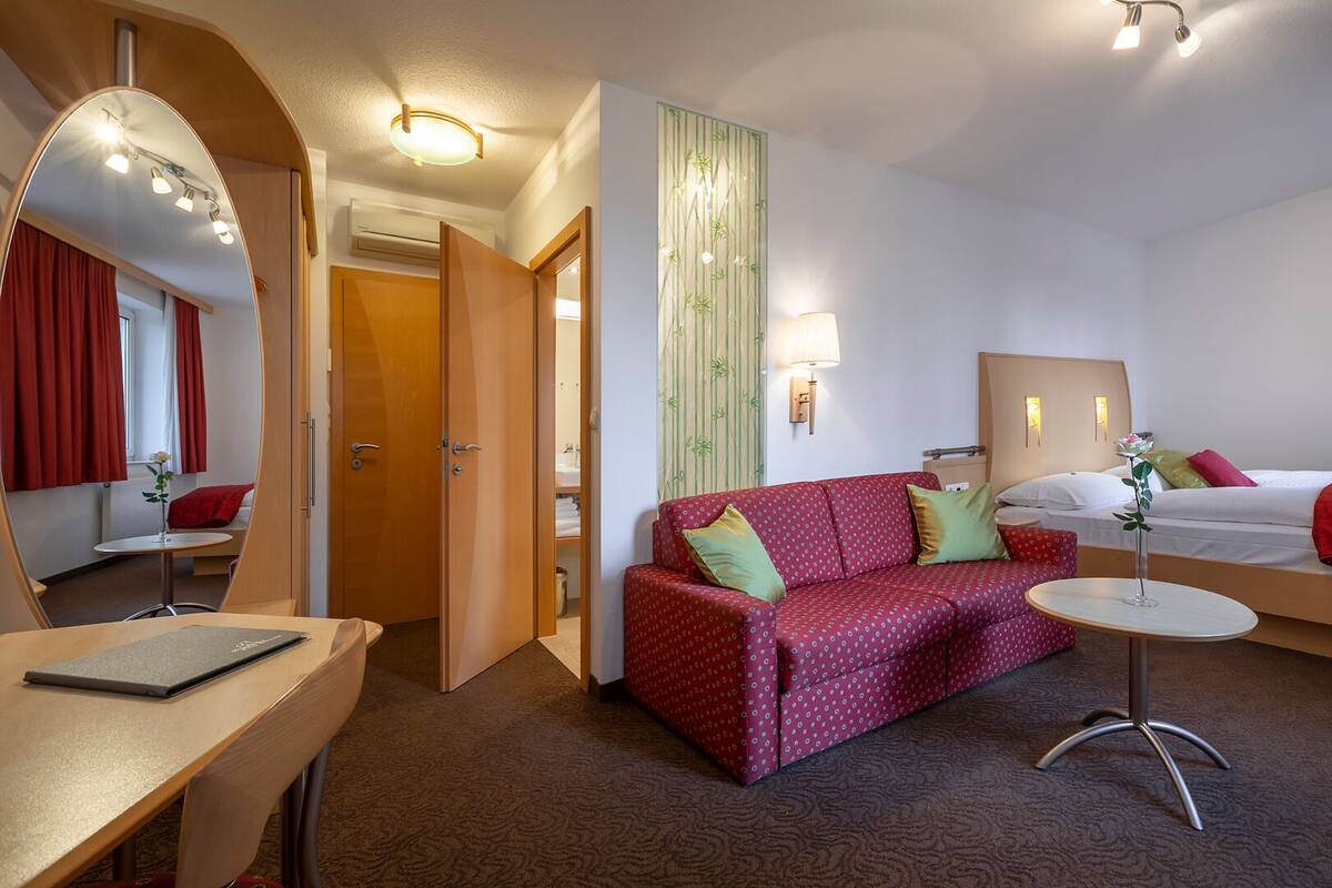 Ein Hotelzimmer mit einem Bett, einem Sofa, einem Schreibtisch und einem Spiegel.