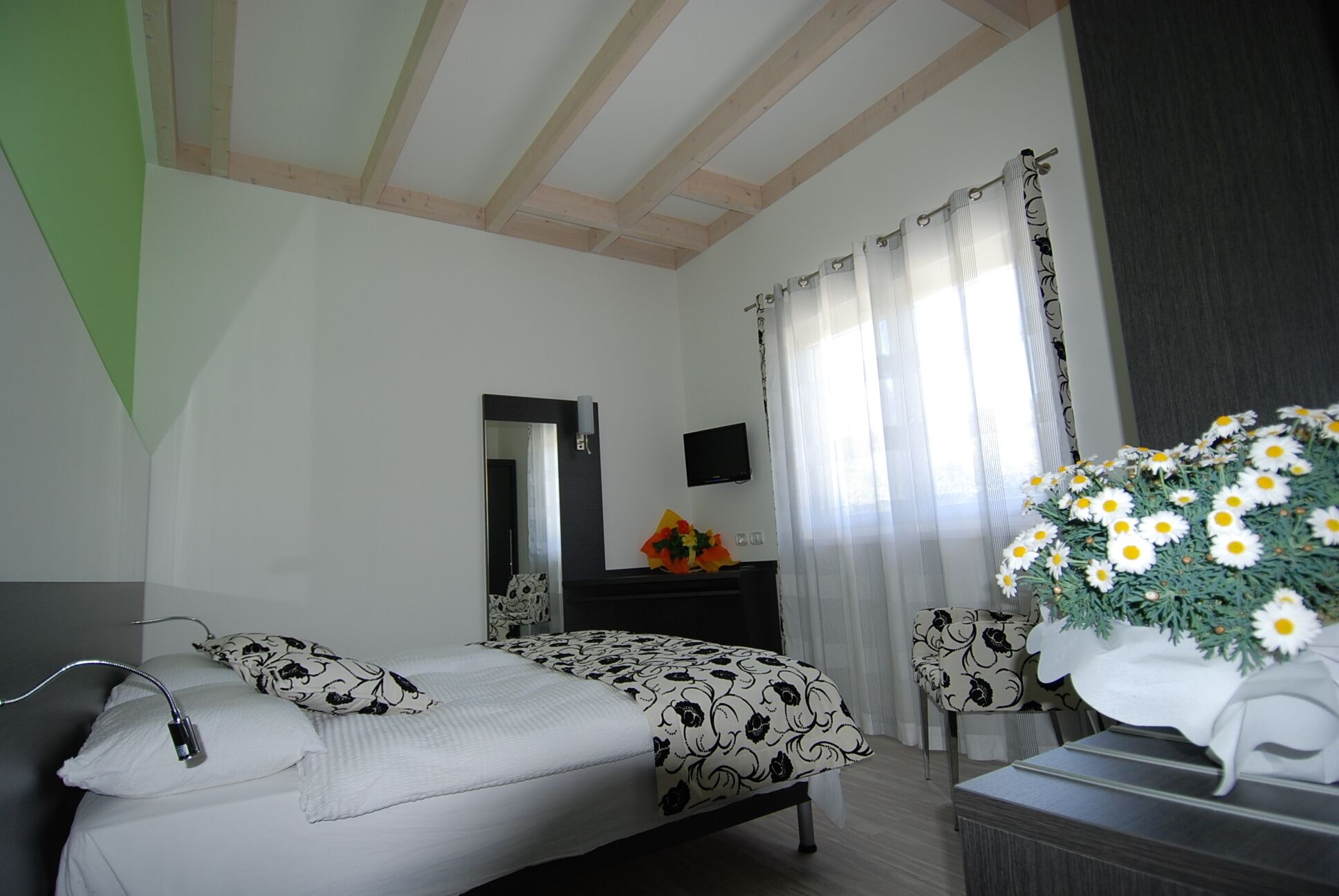 Un dormitorio con cama, cómoda, espejo y ventana con cortinas.